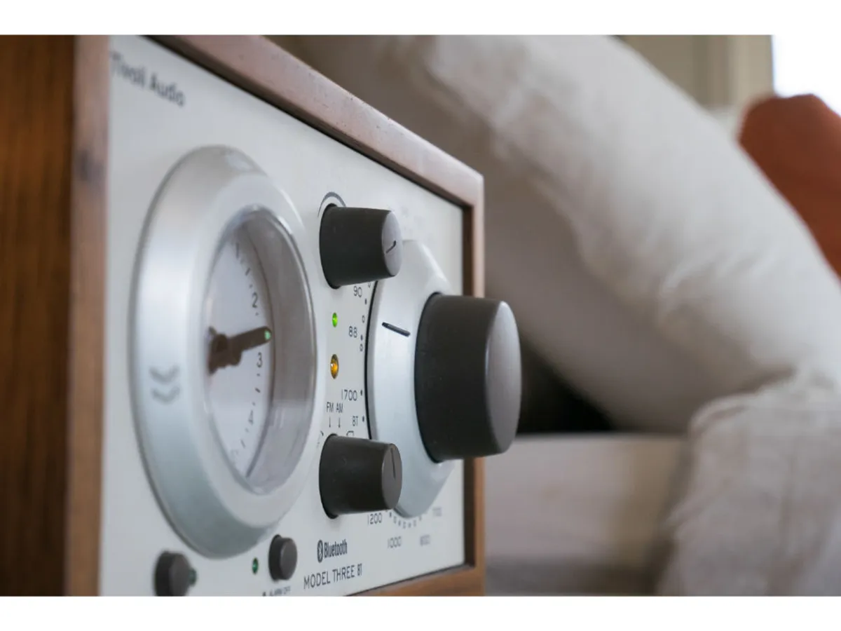 A close-up of vintage audio equipment with tactile control knobs and a dial gauge, evoking a nostalgic mood. The setup hints at the presence of a Tivoli Bluetooth radio, connecting to the section’s mention of music and modern convenience within a setting of historic charm.