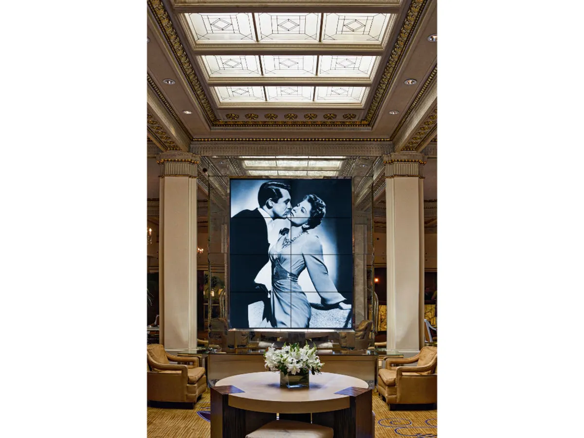 This image features a sophisticated interior with a large vintage photograph display as the focal point. The room is designed with stylish seating and a decorative ceiling, evoking a sense of romantic nostalgia. The ambiance is perfect for guests engaging in social gatherings, intimate conversations, and art appreciation.